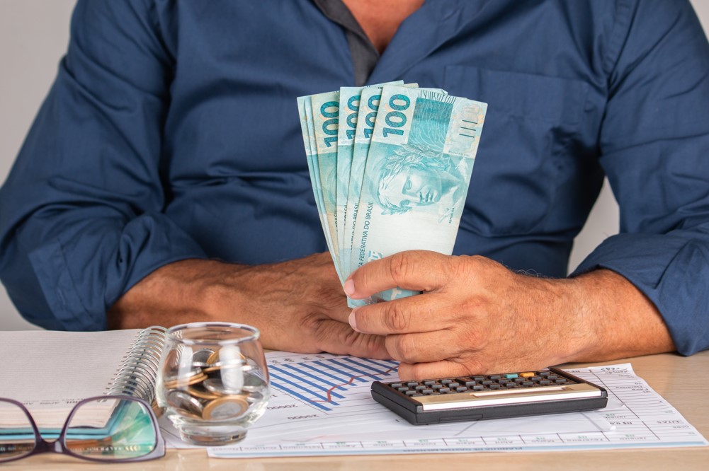 Você fica apertado no fim do mês para pagar as contas? O dinheiro não rende mais como antigamente? Há algumas ideias de renda extra que você pode seguir para ter segurança financeira e dormir muito mais tranquilamente. Além de pagar as despesas do mês sem sufoco, você também vai conseguir guardar um dinheiro para formar uma reserva de emergência ou até mesmo começar a investir. Então, confira essas ideias que separamos para você! Funciona seguir ideias de ganhar renda extra? Antes de tudo, você precisa ter uma coisa em mente. Não adianta conseguir uma renda extra e não ter controle sobre suas finanças. Você vai conseguir gastar ainda mais e criar uma bola de neve de despesas. Por isso, precisa definir quais são as contas fixas, o que é lazer e a quantia que deve guardar. Caso você não saiba ou não se lembre, isso se trata do método 50-30-20, para organizar as contas da casa: 50% do salário deve ser para as despesas, como aluguel, financiamento, mensalidade de escola, contas de luz, água etc; 30% deve ser para os gastos variáveis, e menos importantes para a sobrevivência, isto é, despesas com lazer; E 20% deve ser para pagar dívidas, montar uma reserva financeira, investir ou guardar para projetos futuros. Então, se você seguir esse método, vai conseguir aplicar as ideias de rendas extras e aproveitar o retorno para utilizar no que você precisar. Para te ajudar a ter mais controle sobre sua vida financeira, baixe a planilha! Sicoob. Planilha de orçamento pessoal. Quero baixar grátis. Ideias de renda extra com pouco investimento A melhor forma de ganhar uma renda extra é aplicar seu dinheiro em algum produto financeiro, de uma instituição financeira confiável. Afinal, é a forma mais segura de ter um rendimento no fim do mês e sem fazer muitos esforços. Há muitas promessas na internet de dinheiro rápido e fácil, mas podem se tornar grandes ciladas. Afinal, qual é a segurança real que oferecem? Além do que, muitas das soluções consistem em revender o produto para outras pessoas, o que faz ser necessário dedicar uma boa parte do seu dia para isso. Se você não quer arriscar perder o dinheiro que tem e não tem tempo para trabalhar em um segundo emprego, então deve ficar longe dessas ideias de renda extra pela internet. Enfim, ao contrário do que muitas pessoas pensam, é possível sim investir com pouco dinheiro e ter um retorno satisfatório. Contudo, você deve ter em mente que o rendimento não virá da noite para o dia. É necessário se planejar para saber o quanto de extra você precisa e escolher o investimento que oferece o retorno correspondente. Então, boas ideias de renda extra que você pode seguir são as aplicações de renda fixa, as quais você consegue saber as regras de remuneração. Isto é, se refere como o rendimento é calculado, não necessariamente o valor do retorno. Uma opção complementar são os programas de cashback e pontos que diversos cartões, aplicativos de pagamento e lojas virtuais oferecem. Se você se lembrar de utilizá-los e fazer uma pesquisa antes de realizar qualquer compra, vai conseguir não só economizar um bom dinheiro, como também ter um bom retorno financeiro. E com o dinheiro que você receber, pode juntar para aplicar em diversos investimentos. Leia mais: Como ganhar dinheiro vendendo coisas simples Dicas de investimento Ideias de como ganhar renda extra com investimentos Além do método para dividir o destino da renda, existe a regra dos 80, que vale para para os investimentos. Com o valor que já está separado para isso, você deve subtrair sua idade de 80. O resultado dessa conta será a quantia que você deverá investir em aplicações de renda variável e apenas o restante em renda fixa. Conforme a pessoa fica mais velha, a proporção da renda fixa aumenta, enquanto que a renda variável diminui. Por exemplo, uma pessoa de 25 anos pode investir 55% em renda variável e 45% em renda fixa. E uma pessoa de 55 anos deve investir 25% apenas em renda variável e 75% na renda fixa. Essa regra é apenas um norte para quem não sabe quanto investir nos tipos de investimentos. Portanto, você pode alterar essa proporção conforme desejar. Então, veja a seguir as ideias de como ganhar uma renda extra com investimentos: Conta-capital O primeiro da lista é a conta-capital. Talvez você não tenha escutado muito sobre essa palavra, provavelmente porque está disponível apenas para as cooperativas financeiras. Para se tornar um cooperado, e ter acesso a todos os benefícios da instituição, logo que você se associa, automaticamente é criado uma conta, que é a conta-capital, além da conta-corrente. Nela, você deve depositar um valor inicial, que varia de cooperativa para cooperativa. E para uma determinada quantia depositada, chamada de cota-capital, o cooperado recebe uma cota-parte, que representa sua parte da cooperativa. Então, quanto mais você depositar, mais cotas-partes recebe. Ou seja, maior é sua participação nos resultados de fim de ano da instituição, quando ocorre a distribuição das “sobras” entre todos os cooperados. E ao longo do ano, seu dinheiro fica rendendo, proporcionalmente ao valor e ao tempo que permanecer na conta. Conta-poupança Uma das ideias de fonte de renda extra mais comuns é abrir uma poupança. Afinal, é um dos investimentos mais tradicionais e seguros do mercado. Isso porque a rentabilidade da poupança está atrelada à Taxa Selic, que é a taxa básica de juros da economia. E quem decide seu valor é o Copom (Comitê de Política Monetária), do Banco Central do Brasil. Atualmente, a taxa Selic está em 13,75%, o que significa que o rendimento da poupança é de 6,17% ao ano, ou 0,05% ao mês, que é calculado em cima do valor que você investe. Todo mês, os juros caem na poupança na data de aniversário, que pode ser ou na data de abertura da conta ou na data dos depósitos. A poupança, apesar de ser um investimento, funciona de uma forma parecida com conta-corrente, porque é possível fazer saques, depósitos, transferências, pagamentos e até fazer compras com um cartão de débito. Mas fique atento, não são todas as instituições financeiras que possibilitam tantos serviços. Muitas limitam a quantidade de recursos e movimentações por mês. Então, se é algo que você deseja, precisa procurar uma instituição que ofereça mais liberdade para você utilizar seu dinheiro da forma que você desejar. Fundos de investimento Entre os investimentos de renda variável, contudo ainda seguros, existem os Fundos de Investimentos. Assim como a conta-capital, é uma aplicação coletiva, porque é um investimento que mais de uma pessoa realiza. Funciona da seguinte forma: um grupo de pessoas investe nos Fundos, que é administrado por uma pessoa, que pode ser da escolha do grupo ou da instituição financeira. Isso vai depender de onde você escolher investir. E por causa disso, existe uma taxa de administração e uma quantia mínima de aplicação. Enfim, o administrador fica responsável por controlar as aplicações, que são variadas. Há uma porcentagem de investimentos de renda fixa e outra de renda variável. E os resultados são divididos proporcionalmente entre os membros, de acordo com o valor que cada um investiu. LCA e LCI Os investimentos LCA (Letra de Crédito Imobiliário) e LCI (Letra de Crédito do Agronegócio) servem para captar recursos para os setores imobiliário e agropecuário, justamente para estimular seu desenvolvimento no país. E ambos são importantes para o crescimento da economia. Então, ao contrário de um empréstimo, é o investidor que empresta dinheiro para alguma instituição financeira e, em troca, recebe um juros em cima do valor. Esses tipos de investimentos são de renda fixa, mas podem ter taxas pré ou pós-fixadas. A taxa pré-fixada significa que você sabe exatamente o valor do rendimento no início da aplicação. Já a taxa pós-fixada você só sabe o valor exato no final da aplicação. Esse tipo de investimento acompanha as taxas de CDI (Certificado de Depósito Interbancário), que é um tipo de empréstimo realizado apenas entre instituições financeiras, com prazo de um dia útil. Apesar da sigla ser parecida com CDB, não é a mesma coisa, como você vai ver a seguir. CDB e RDC No fim da lista de ideias de como ter uma renda extra, tem os investimentos: Certificado de Depósito Bancário (CDB) e Recibo de Depósito Cooperativo (RDC). Eles são bem tradicionais e também funcionam como um empréstimo para as instituições, nos quais os investidores recebem um juros por isso. O primeiro é específico para instituições financeiras convencionais, enquanto que o segundo é voltado apenas para as cooperativas financeiras, como o Sicoob. Ambos têm liquidez diária, o que os torna muito atrativos, porque isso significa que você não tem um prazo determinado para fazer um resgate, pode fazer isso em qualquer dia que desejar. Assim como LCA e LCI, também possuem títulos pré e pós-fixados. Contudo, o RDC oferece duas opções: RDC Curto e RDC Longo. O curto é mais indicado para pessoas que não sabem quando vão fazer um resgate, enquanto que o longo é mais aconselhado para quem pretende fazer pequenos resgates ao longo do investimento. Se você ficou interessado em investir em qualquer um desses investimentos, abra uma conta na agência Sicoob mais próxima de você! Você também pode ter uma conta digital no Sicoob, baixe o App Sicoob e abra sua conta agora mesmo! Aqui, como cooperado, você tem muitas vantagens que poucas instituições financeiras oferecem. Por sermos um sistema de cooperativas, você tem acesso às taxas mais justas do mercado, porque nosso foco não é o lucro, e sim a liberdade e justiça financeira. Mais que uma escolha financeira. Com a conta digital do Sicoob, você ganha mais e controla a vida financeira com alguns cliques. Quer ver? Diversidade de soluções financeiras para cuidar do seu dinheiro; Transações financeiras feitas de formas simples, segura e sem sair de casa através do app Sicoob; Participação dos resultados da cooperativa; Você ganha com nosso cooperado e ainda ajuda a investir na região. Sicoob-Quero abrir minha conta.