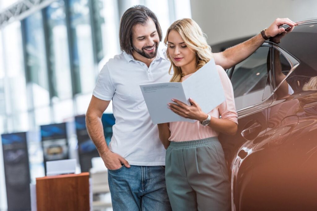 Casal de homem e mulher analisando o contrato para saber se vale a pena financiar um carro.